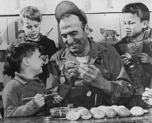 Sgt. George A. Crist, 1st cook, US 8th AF/96th Bombardment Group, teaches British lads the art of Easter egg decorating.
