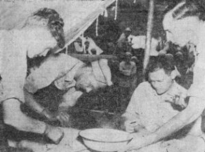 T/5 Robert Kingston, Maj. Robert E. Pennington, Lt. E. Boyd (seated) and T/5 Joseph H. Hill operating on Chinese soldier on Salween Front. 